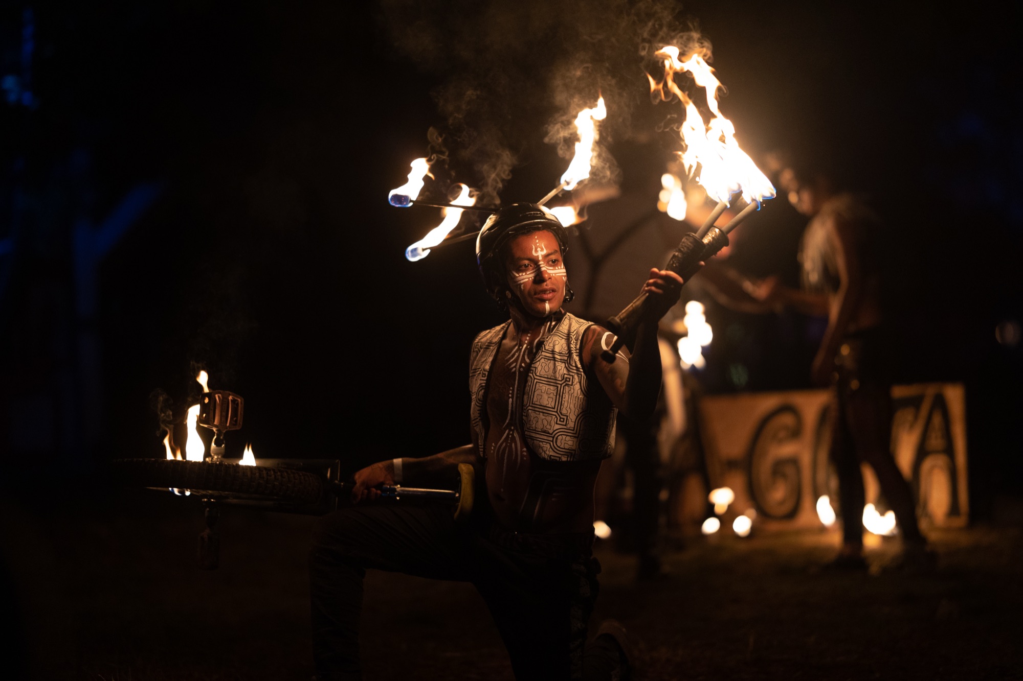 A fire performer spinning props beside burning letter signs