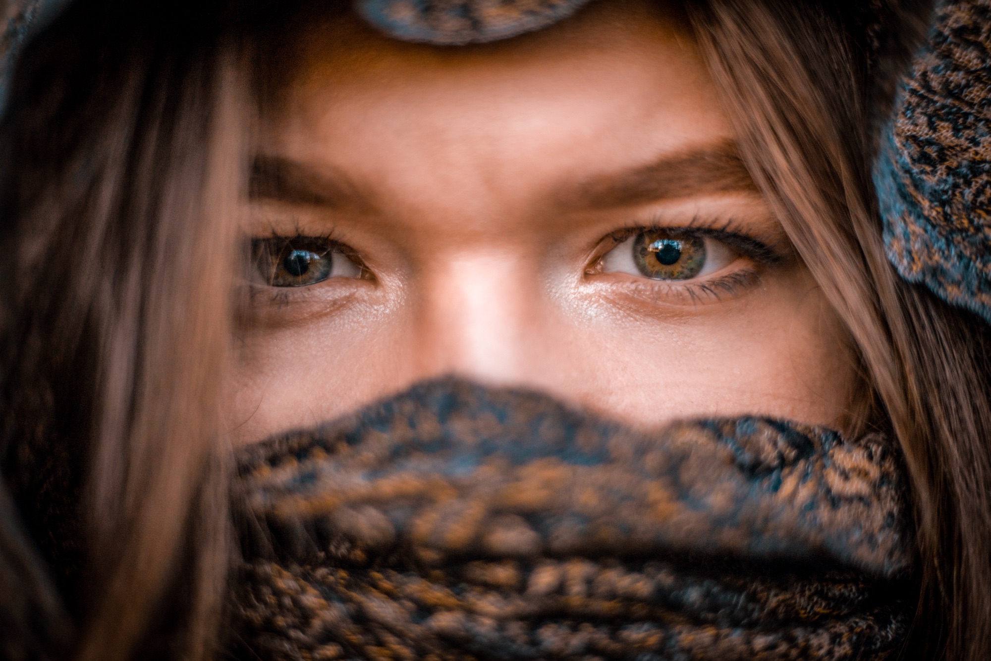Close-up portrait of a woman's eyes over a patterned scarf